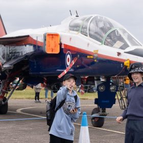 Two boys pointing and looking at something with a red, white and blue Jaguar behind them.
The RAF Cosford Airshow, Sunday 9th June 2024 is the primary airshow of the Royal Air Force attracting in excess of 55,000 visitors it is one of the biggest events in the West Midlands. This Years theme was ‘Take Flight’ with displays, events and activities aiming to drive potential new recruits to kickstart their interest of a career in the RAF and develop an understanding of what the British Military, Allied Forces and Sister Services do for the defence of the United Kingdom. Visitors are able to get close to the cutting edge of technology with RAF Aircraft and unique attractions across the show ground and immerse themselves in a thrilling action-packed flying display programme.
The RAF Cosford Airshow is an excellent way for the Ministry of Defence to engage with the public and showcase the Royal Air Force’s capabilities and to celebrate the service’s history while looking ahead to the next generation of people and technology.
RAF Cosford in Shropshire is a major part of the Defence College of Technical Training (DCTT). It is at the centre of the RAF’s mission to deliver flexible, affordable, modern and effective technical training that meets the needs of the UK’s Armed Forces now and into the future. RAF Apprenticeships delivered at RAF Cosford were recently recognised as ‘Outstanding’ by Ofsted. RAF Cosford is also home to the popular RAF Museum and the world-renowned Cosford Airshow.